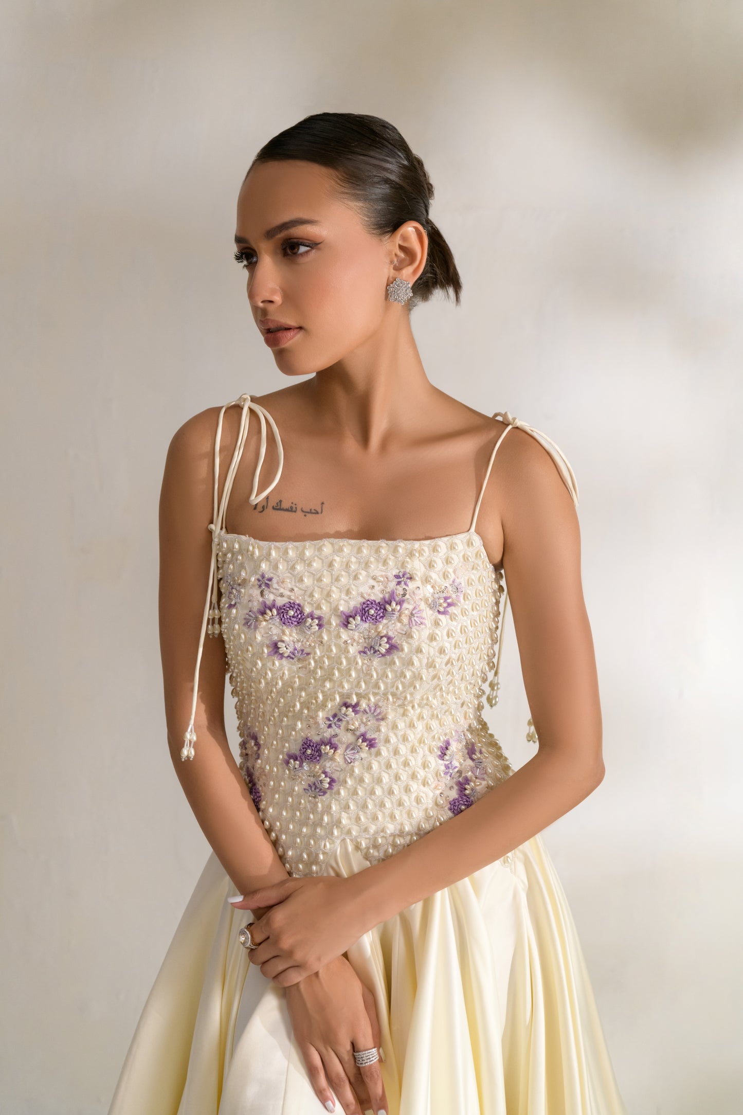 Designer gown featuring square neckline and beaded shoulder ties